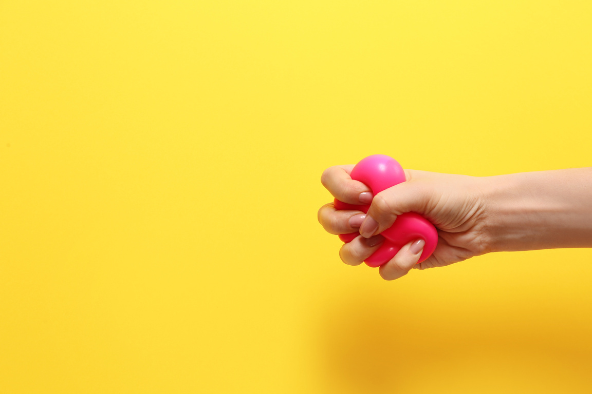 Hand Squeezing Stress Ball on Color Background